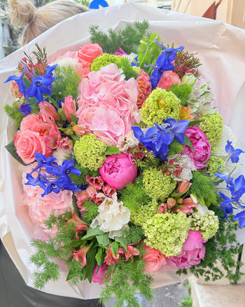 Antonia Flowers Roma, bouquet floreale con ortensie rosa, rose, delphinium blu, fiori verdi e foliage naturale