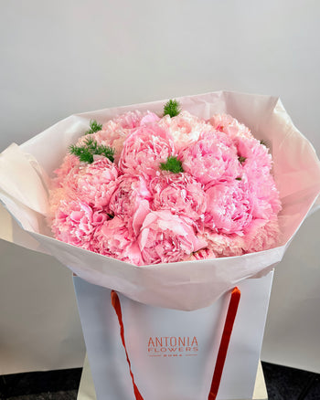 Antonia Flowers Roma, bouquet di peonie rosa avvolto in carta chiara nella shopper del flower atelier